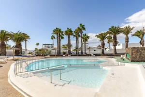 a swimming pool with palm trees in a resort at Coqueto apart en Las Coronas in Costa Teguise