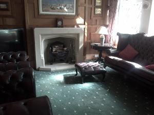 a living room with a fireplace with a couch and a chair at Lewinsdale Lodge in Weston-super-Mare