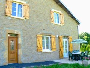 a house with a table and chairs and an umbrella at La ferme de la fontaine in Douzy
