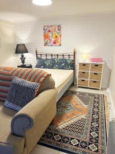 a bedroom with a bed and a couch and a rug at Guest suite-2 beds,private entry, bathroom & laundry in Wollongong