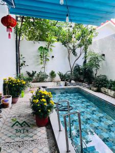 a swimming pool with flowers and plants next to a building at Homestay Byta House in Kinh Dinh