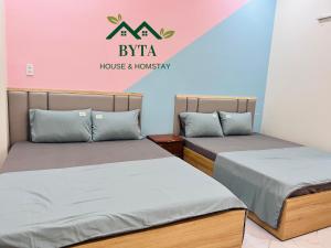 two beds in a room with a house and tourism sign at Homestay Byta House in Kinh Dinh +20 photos