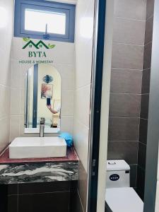 a bathroom with a sink and a mirror and a toilet at Homestay Byta House in Kinh Dinh
