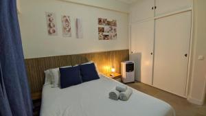 a bedroom with a large white bed with blue pillows at Caparica Beach Charming in Costa da Caparica