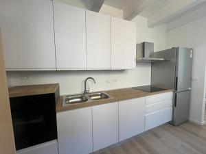 a kitchen with white cabinets and a stainless steel refrigerator at Delizioso Attico Calle Lunga 2 in Grado