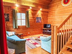 a log cabin living room with a tv and two chairs at Holiday Home Haus Fries by Interhome in Unterbergern