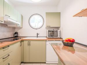 a kitchen with white cabinets and a bowl of apples on a counter at Apartment Le Cesarée-1 by Interhome in Fréjus