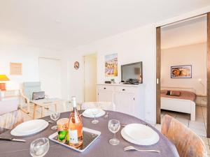 a dining room with a table with wine bottles and glasses at Apartment Le Cesarée-1 by Interhome in Fréjus