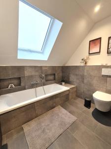 une salle de bain avec baignoire et toilettes et un puits de lumière dans l'établissement Winterberg Appartement 21133, à Winterberg 36 autres photos