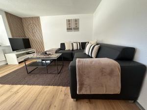 a living room with a black couch and a table at Apartment Enzian by Interhome in Saas-Grund
