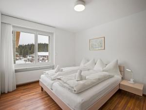 a white bed in a room with a window at Apartment Nr-14 Haus Astoria by Interhome in Lenzerheide