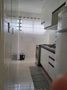 a white kitchen with a stove and a refrigerator at Apartamento Bertioga in Bertioga