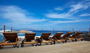 a row of chaise lounges sitting on a deck at Vrahos Boutique Hotel in Karavostasi