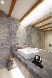 a bathroom with a sink and a stone wall at Vrahos Boutique Hotel in Karavostasi