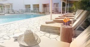 a swimming pool with chairs and a table with a drink at Blanc Sable Hôtel in Golfe-Juan