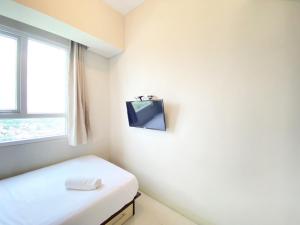 a room with a bed and a tv on the wall at Deluxe and Cozy 2BR Apartment at Skyland City Jatinangor By Travelio in Sumedang