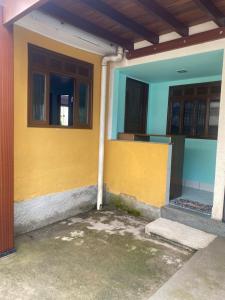 a building with a yellow and blue wall and two windows at Casa da Inês in Santa Teresa