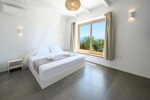 a white bedroom with a bed and a window at Villa Porto Mongonisi in Porto Ozias