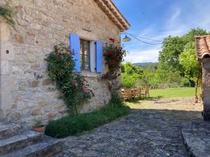 una casa de piedra con persianas azules y flores en Mas de la Giralde - Gites, en Payzac