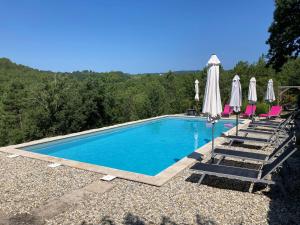 una piscina con sillas y sombrillas en Mas de la Giralde - Gites, en Payzac
