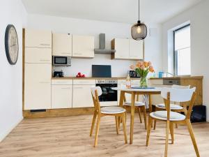 a kitchen with white cabinets and a table and chairs at Ferienwohnung Windflüchter Parkvillen Carlota und Candela Baabe in Baabe