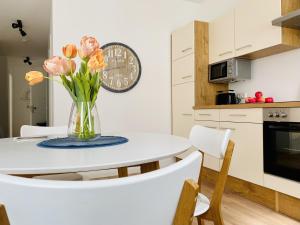 a white kitchen with a vase of flowers on a table at Ferienwohnung Windflüchter Parkvillen Carlota und Candela Baabe in Baabe +9 photos