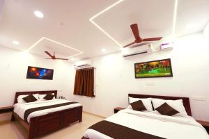 une chambre avec deux lits et une télévision au mur dans l'établissement MM Comfort Inn, à Pondichéry 17 autres photos