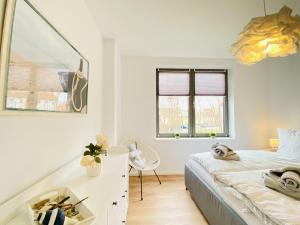 a white bedroom with a bed and a desk at Ferienwohnung Windflüchter Parkvillen Carlota und Candela Baabe in Baabe