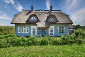 Ferienhaus Strandflieder 05 Feriendorf Klein Stresow Rügen by ruyastay في بوتبوس: منزل أزرق مع سقف من القش