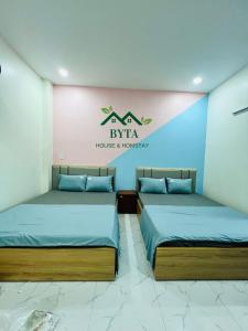 two beds in a room with a sign on the wall at Byta House Homestay in Kinh Dinh