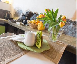 een tafel met een vaas met bloemen en een fruitschaal bij Etna Dependance in Santa Venerina