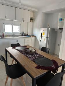 a kitchen with a wooden table with chairs and a refrigerator at Alba II - Departamento 2 ambientes in Posadas