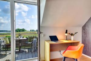 プットブスにあるFerienwohnung Wiesenpieper 07 im Wreecher Idyll Rügen by ruyastayのデスクとバルコニー付きのホームオフィス