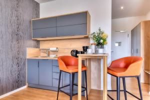a kitchen with orange bar stools and a sink at Ferienwohnung Mauersegler 14 im Wreecher Idyll Rügen by ruyastay in Putbus +4 photos