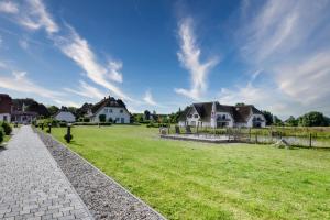 a grassy field with houses and a fence at Ferienwohnung Grünfink 04 im Wreecher Idyll Rügen by ruyastay in Putbus