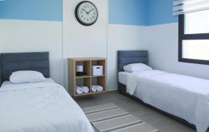 a bedroom with two beds and a clock on the wall at Neron Family Sea View Apartment in Caesar Resort & SPA, Long Beach in Perivolia tou Trikomou +63 photos