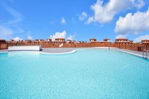 a large blue swimming pool with a wooden fence at Casa Bonita Lajares Fuerteventura in Lajares