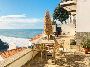 einen Tisch mit einem Sonnenschirm, Stühlen und dem Meer in der Unterkunft Casa Zen in Azenhas do Mar