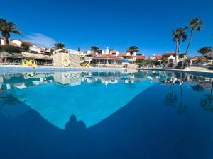una persona sentada frente a una gran piscina en Lola Sunset Place Heated Pool, en San Miguel de Abona