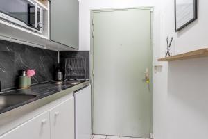 a kitchen with white cabinets and a glass door at L'Oasis - Studio à 350m de la mer & du centre ville in Saint-Nazaire +11 photos