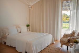 a white bedroom with a white bed and a window at La Farm Baleares in Santa Maria del Camí +28 photos