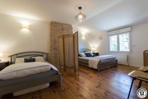 a bedroom with two beds and a brick wall at Gîte des moulins in Castelnau-dʼEstrétefonds