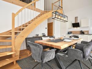 a dining room with a wooden table and chairs and a staircase at Gipfelblick Lodge 5 Pruggern by AA Holiday Homes in Pruggern