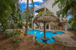 a house with a pool and a straw umbrella at Margarita-Ville in Holmes Beach