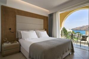 a bedroom with a bed and a large window at Lindos Royal Resort in Líndos