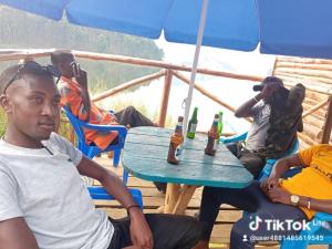 un grupo de personas sentadas alrededor de una mesa con botellas de cerveza en Weaver Bird Hostel, en Rubanda