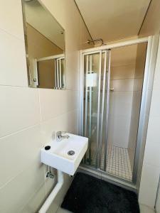 a white bathroom with a sink and a shower at Cozy One-bedroom Apartment near GrandPalm Resort Block 5, Gaborone, Botswana in Mogoditshane