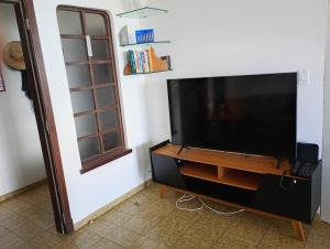 a flat screen tv sitting on a stand next to a wall at PITANGUEIRAS LINDO FRENTE AO MAR 4 QUARTOs in Guarujá