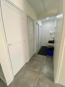 a room with white doors and a hallway with a trash can at Casa de Oliveira Hostel in Torres