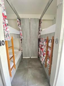 a small room with bunk beds and shelves at Casa de Oliveira Hostel in Torres